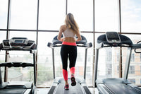 A fit woman's torso visible running on a treadmill in a gym representing the question of does cardio cancel out what you eat for weight loss and why exercise alone is not enough.