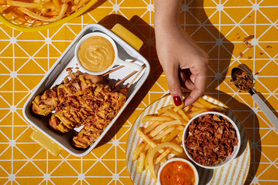 Hand reaching for fried snacks and fries on a bright table