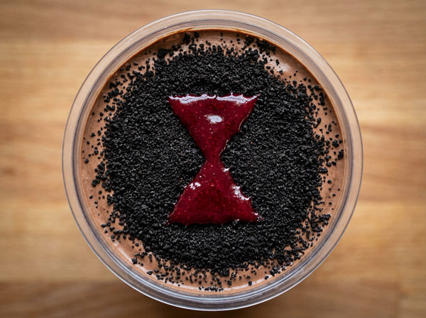 Black Widow Ninja Creami recipe made with CRUSHS chocolate protein ice cream mix, crushed chocolate sandwich cookies, and a raspberry sauce hourglass.