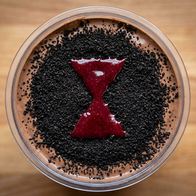 Black Widow Ninja Creami recipe made with CRUSHS chocolate protein ice cream mix, crushed chocolate sandwich cookies, and a raspberry sauce hourglass.