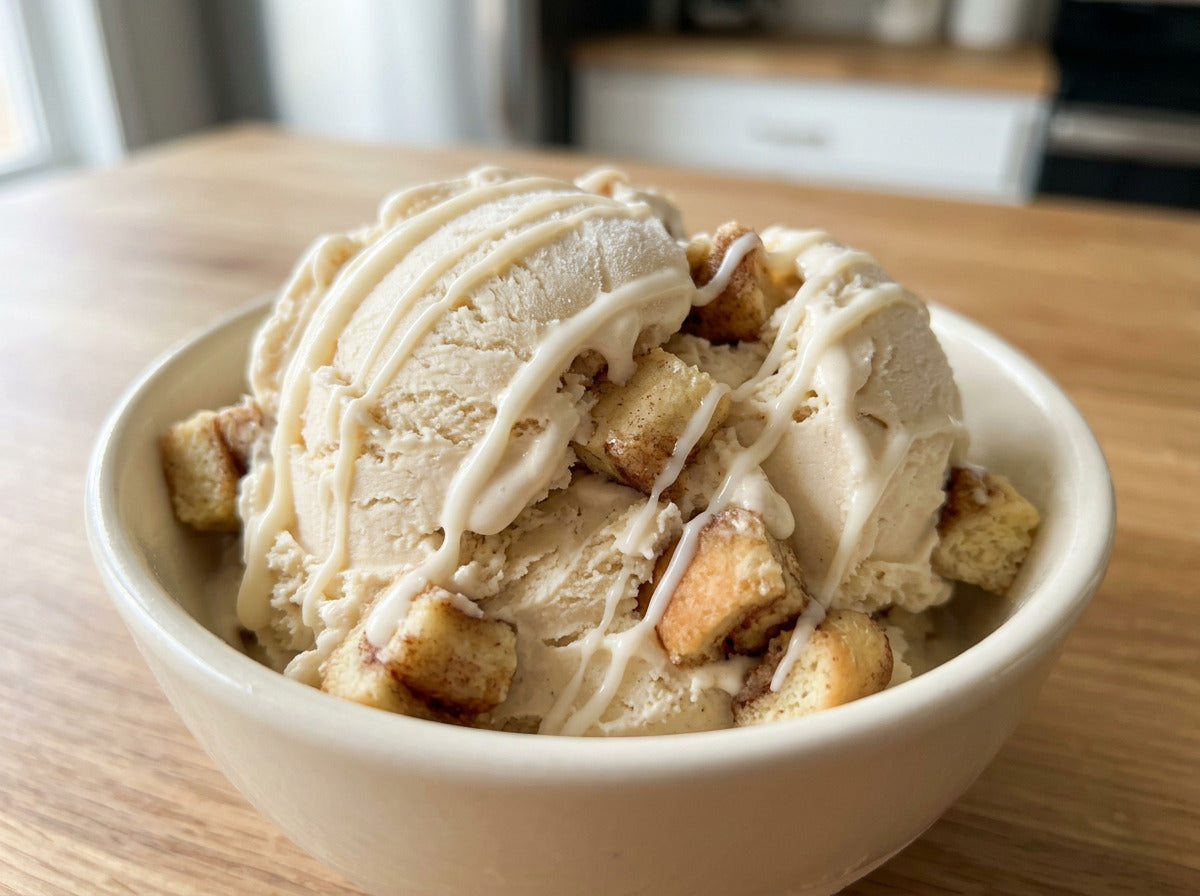 Cinnamon Roll Ninja Creami recipe made with CRUSHS vanilla protein ice cream mix, cinnamon roll pieces, and a cream cheese icing drizzle.