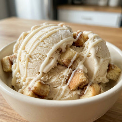 Cinnamon Roll Ninja Creami recipe made with CRUSHS vanilla protein ice cream mix, cinnamon roll pieces, and a cream cheese icing drizzle.