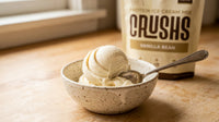 A creamy scoop of vanilla protein ice cream in a speckled ceramic bowl with a CRUSHS Vanilla Protein Ice Cream Mix bag visible behind it representing one of the most practical high protein desserts for GLP-1 users who still have sweet cravings.