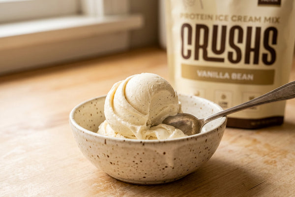 A creamy scoop of vanilla protein ice cream in a speckled ceramic bowl with a CRUSHS Vanilla Protein Ice Cream Mix bag visible behind it representing one of the most practical high protein desserts for GLP-1 users who still have sweet cravings.