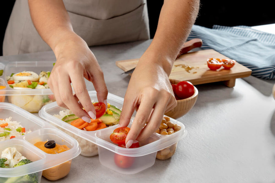 A person's hands visible arranging a meal prep container with fresh vegetables and protein showing the food environment setup that makes how to make healthy eating habits stick a systems problem not a willpower problem.