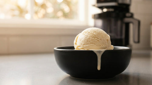 A creamy dense scoop of vanilla protein ice cream in a sleek black bowl slightly melting showing the finished result of how to make protein ice cream Ninja Creami style with the right base and respin.