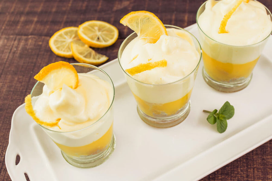 Lemon yogurt parfait glasses with whipped cream and lemon slices as a low calorie Mother's Day dessert.
