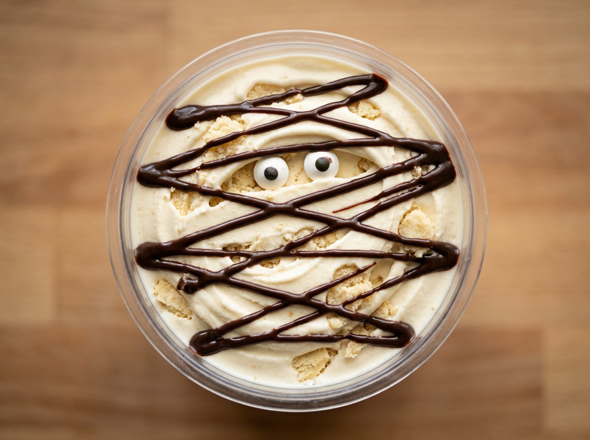 Mummy Wrap Ninja Creami recipe made with CRUSHS vanilla protein ice cream mix, shortbread crumbles, chocolate syrup bandages, and candy eyeballs.