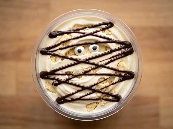 Mummy Wrap Ninja Creami recipe made with CRUSHS vanilla protein ice cream mix, shortbread crumbles, chocolate syrup bandages, and candy eyeballs.