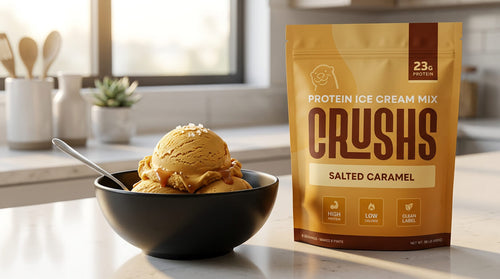 A CRUSHS Salted Caramel Protein Ice Cream Mix bag beside a creamy scoop of salted caramel ice cream in a black bowl representing the best protein ice cream mix for Ninja Creami that delivers 23g of protein at 180 calories with 0g added sugar.