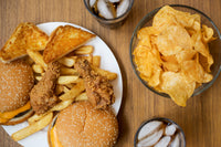 Overhead view of junk food including a burger, fries, and chips on a wooden table.