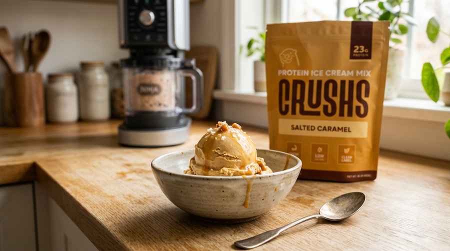 A creamy scoop of salted caramel protein ice cream in a ceramic bowl with a CRUSHS Protein Ice Cream Mix bag and a Ninja Creami machine blurred in the background representing the protein ice cream results you can expect whichever Ninja Creami model you choose.