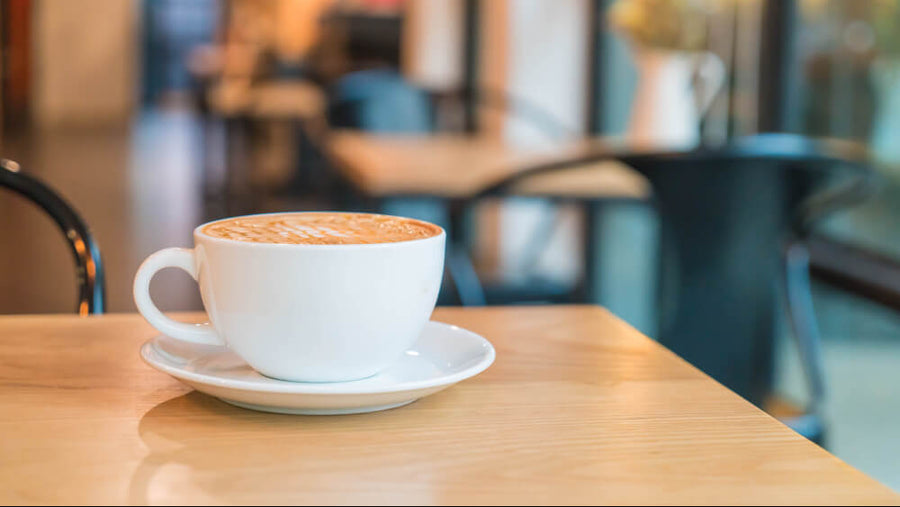 Latte in a white cup on a cozy cafe table.