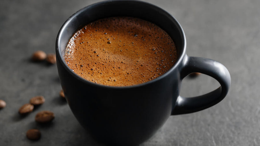 Close-up of a dark coffee mug, representing caffeinated drinks as one of the bad foods to eat before bed.