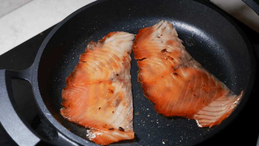 A salmon fillet cooking in a pan showing a high protein meal that supports muscle recovery the same way eating ice cream after a workout can when the protein content is right.