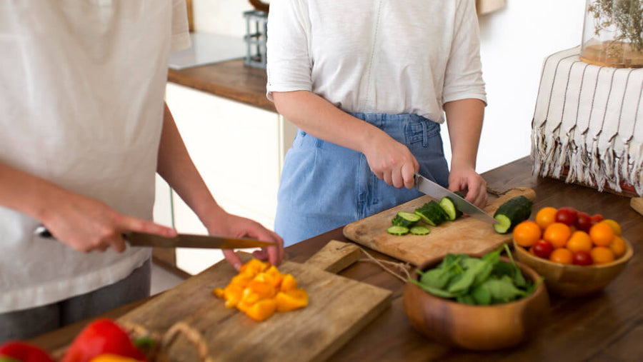 Woman chopping fresh vegetables in a bright kitchen as a shared experience gift for health conscious moms on Mother's Day.