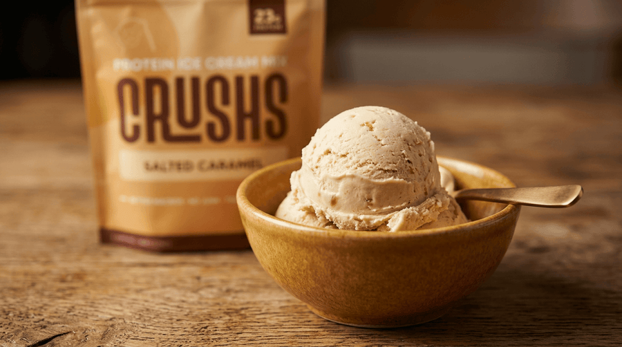 Scoop of CRUSHS Salted Caramel protein ice cream in a wooden bowl with CRUSHS bag in the background.
