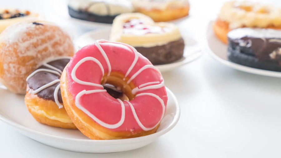 Assorted donuts on a white plate, representing high-sugar desserts as bad foods to eat before bed.