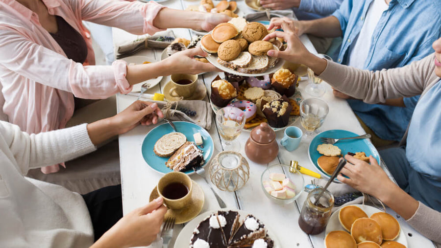 Family hands reaching across a shared dessert table as part of a healthy Mother's Day dessert board spread