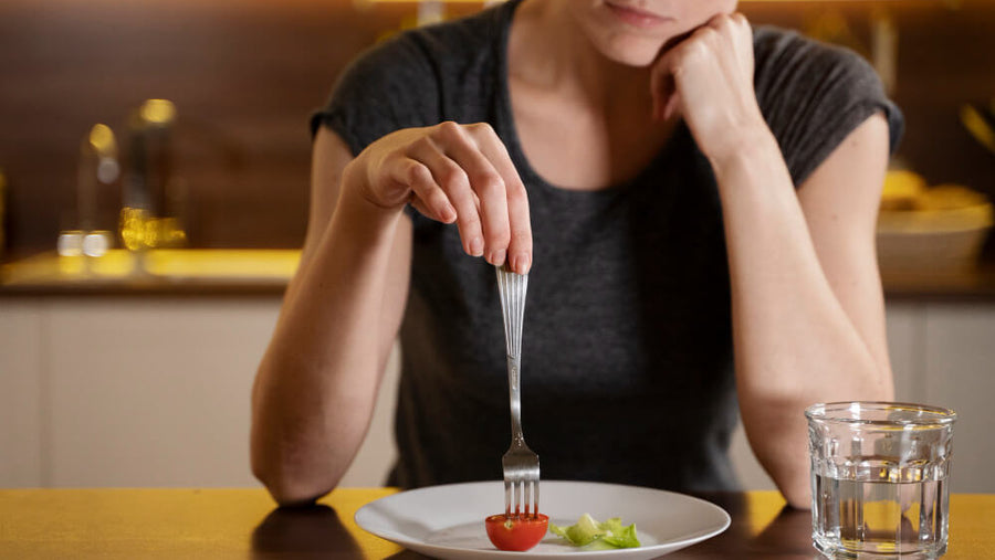 A person's hands visible pushing food around a small portion on a plate representing one of the most common fitness nutrition mistakes of eating too little while training consistently.