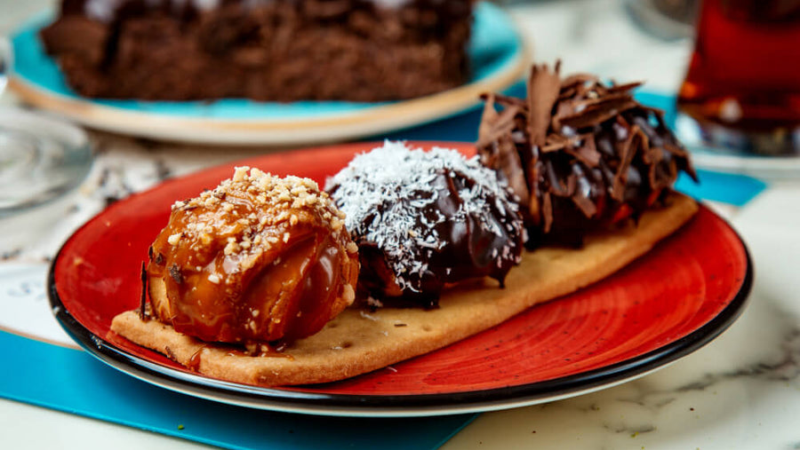 A plate of chocolate cake and sweet pastries representing the kind of high sugar foods that trigger why sugar cravings after eating keep happening through a rapid blood sugar spike and crash cycle.