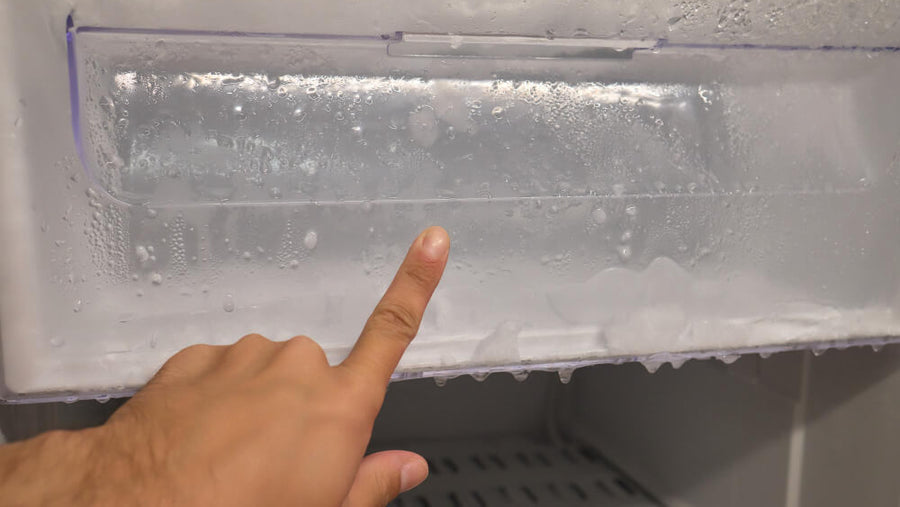 A hand pointing to the back of a freezer showing where to place a Ninja Creami pint for the best freeze results when learning how to make Ninja Creami creamy every time.