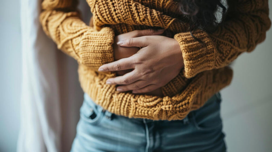 A person's torso and hands visible clutching their stomach representing the gut bacteria connection to why sugar cravings after eating feel like genuine hunger signals from the gut-brain axis.