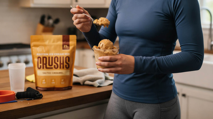A fit girl's torso and arms in gym clothes holding a bowl of salted caramel ice cream with a CRUSHS bag visible beside her showing that eating ice cream after a workout is a real and effective recovery option.