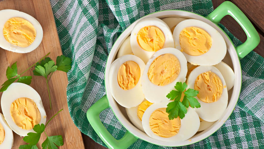 A plate of sliced hard boiled eggs on a kitchen surface showing one of the simplest and most portable ready-made high protein meals available at any grocery store.