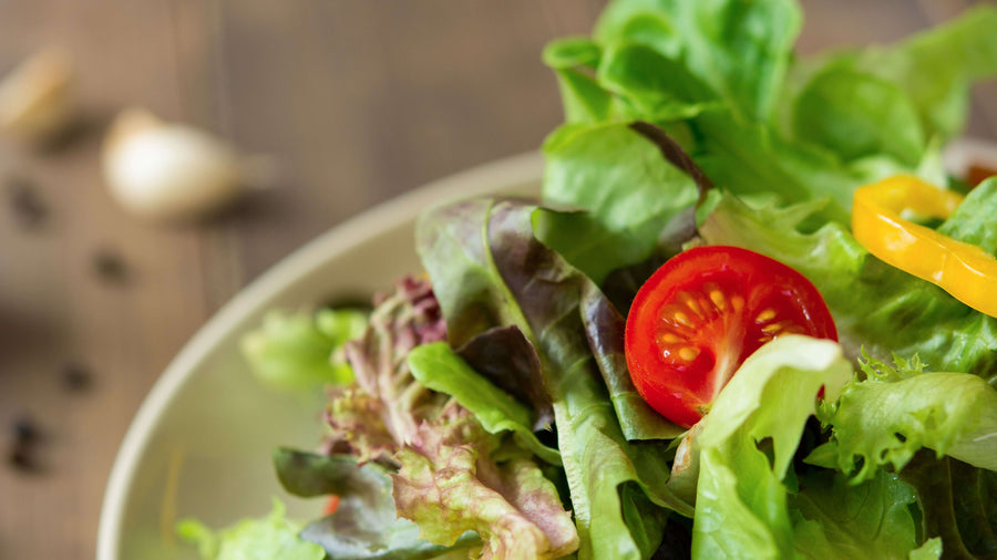 A fresh healthy salad bowl on a wooden surface representing the kind of low calorie dense meal that can quietly cause eating healthy makes me tired when total intake drops too low.
