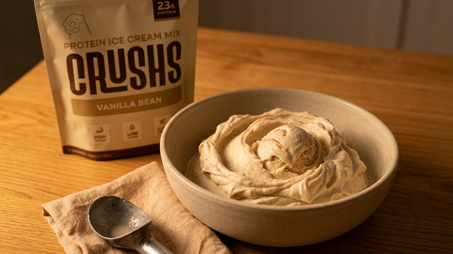 A creamy scoop of vanilla bean protein ice cream in a ceramic bowl with a CRUSHS Vanilla Bean Protein Ice Cream Mix bag visible behind it representing a daily dessert habit worth building into how to build a summer routine.