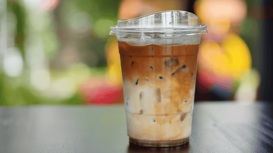 A tall iced coffee in a plastic takeout cup showing the caffeine content of iced coffee vs cold brew.