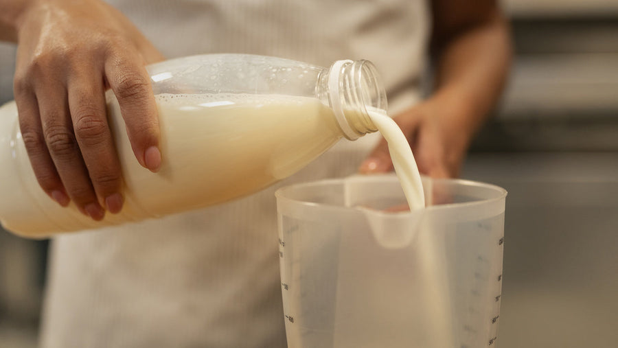 A glass of fresh whole milk being poured, representing the dairy source behind milk protein isolate and its casein-rich protein content.