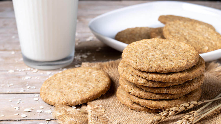 A stack of oatmeal cookies on a wooden surface beside a glass of milk representing a sweet treat that can be made higher protein for GLP-1 users looking for high protein desserts that still feel like real food.