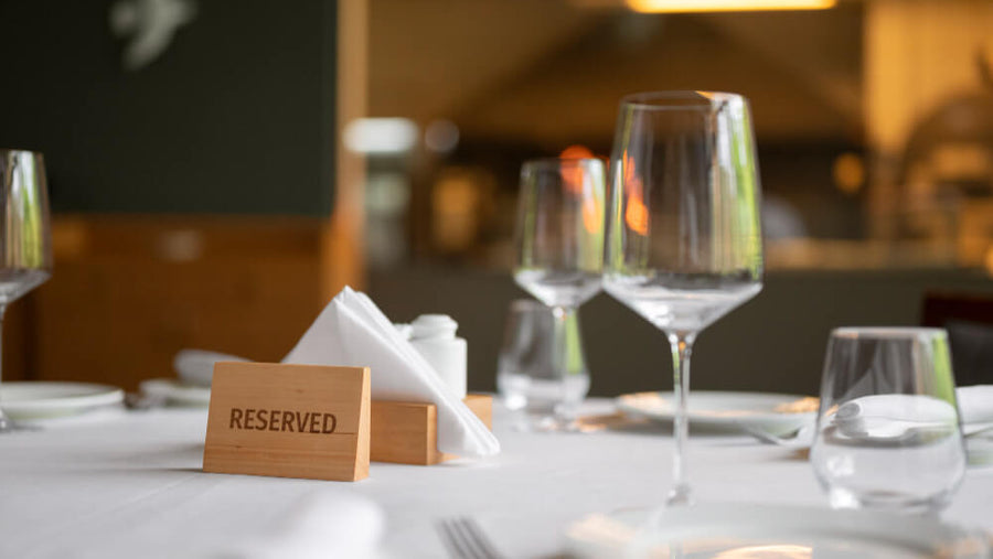 A reserved restaurant table with wine glasses and candles as part of how to celebrate Mother's Day with a special lunch or brunch.