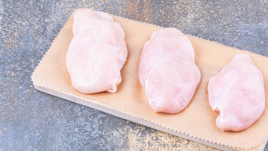 Raw skinless chicken breasts on a cutting board representing one of the highest protein foods for people figuring out do i need protein if i dont exercise and how to hit their daily target.