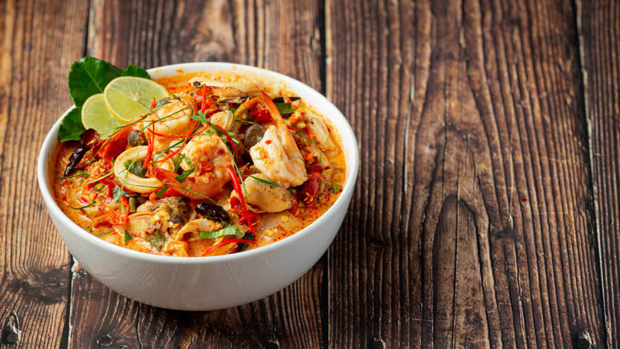 Bowl of spicy Thai dish with chili and lime, representing spicy food as one of the bad foods to eat before bed.