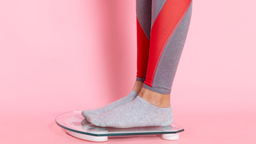 Person in athletic wear stepping on a bathroom scale