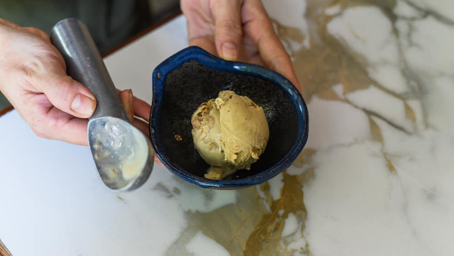 A person's hands holding a bowl of freshly spun ice cream in a cozy kitchen setting representing who benefits most from the ninja creami vs ice cream maker choice.